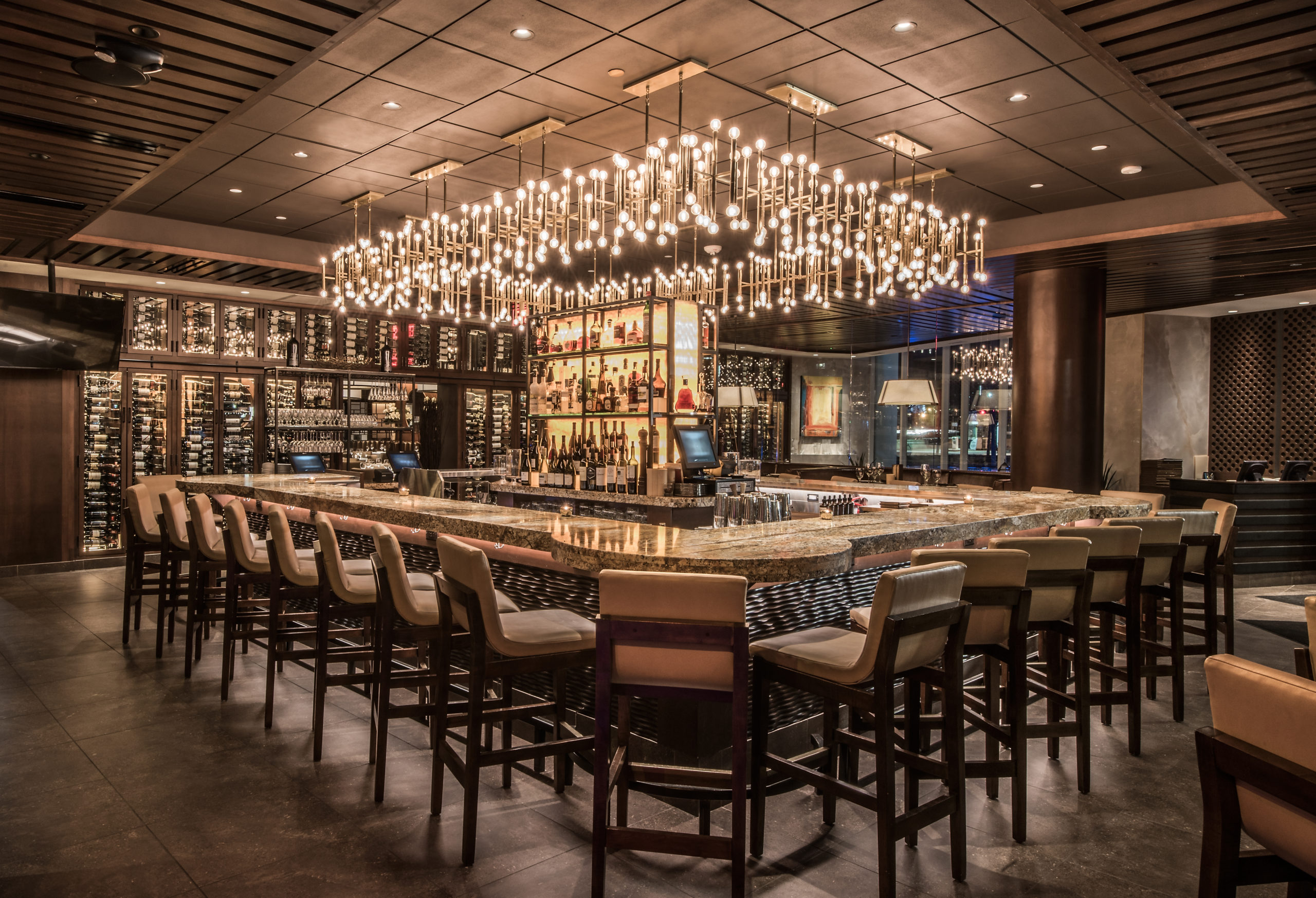 women in lighting design created hanging lights over bar with stools
